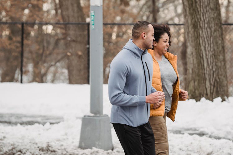 Ethnic Man And Woman Jogging Together On Winter Street