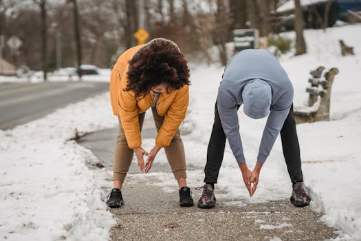 Full length faceless ethnic male trainer and plump female stretching body and bending down before working out on snowy sidewalk on winter day
