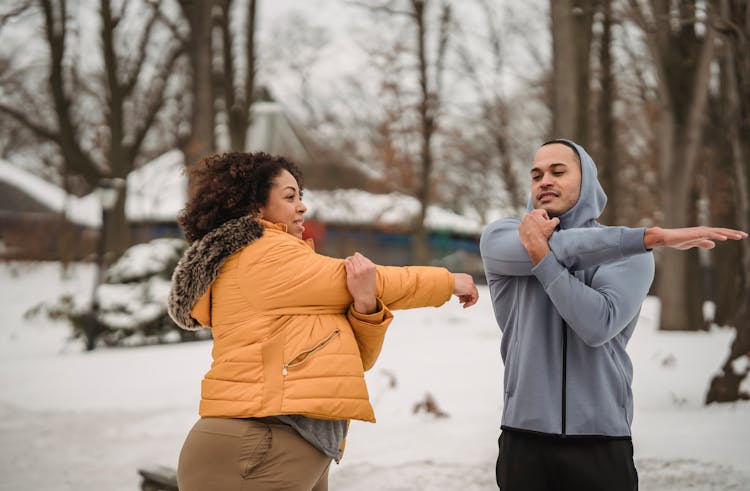 Content Diverse Sportspeople Doing Triceps Stretch In Winter Park