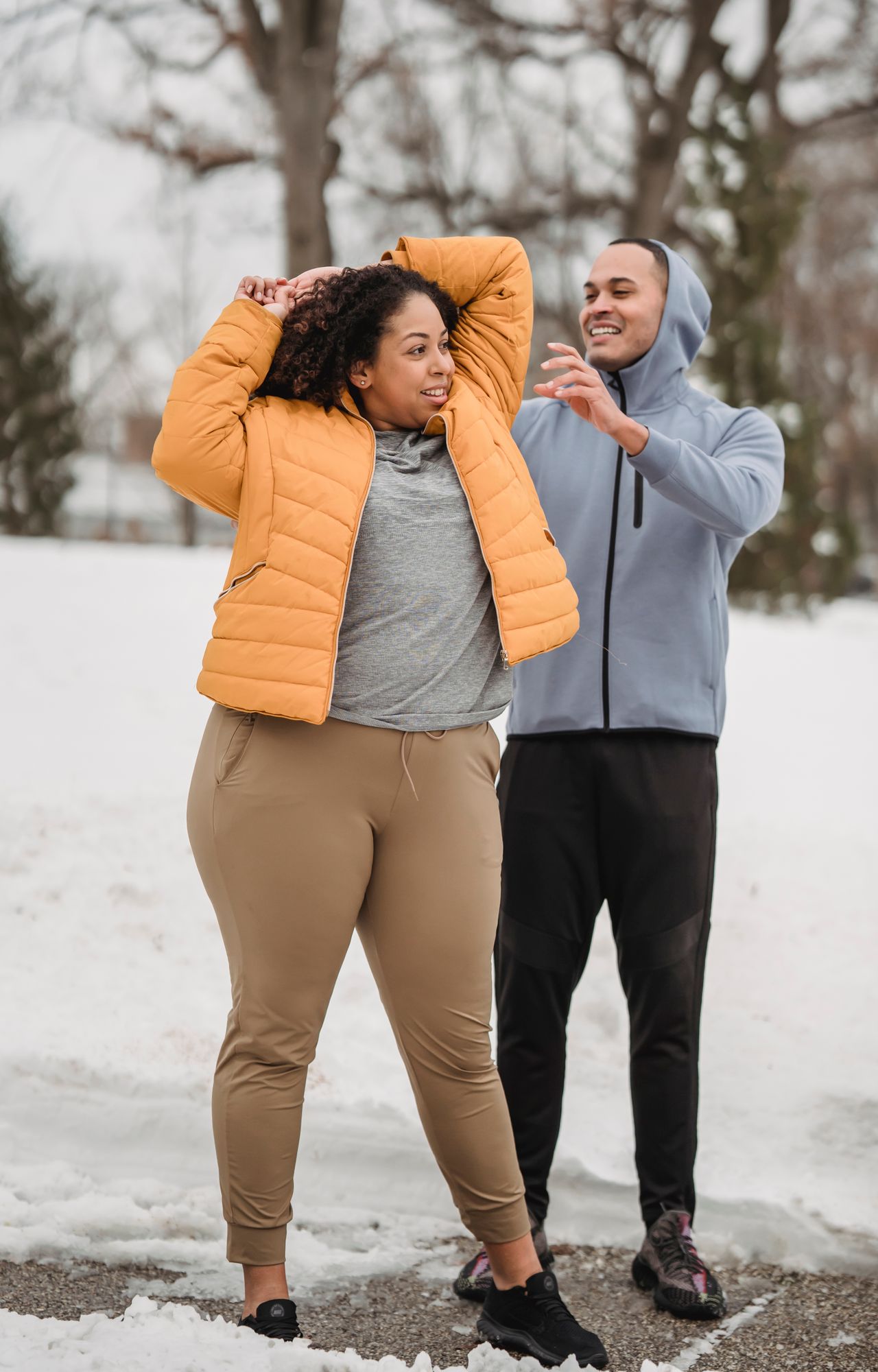 Plus-size woman warming up with a personal trainer in a snowy park