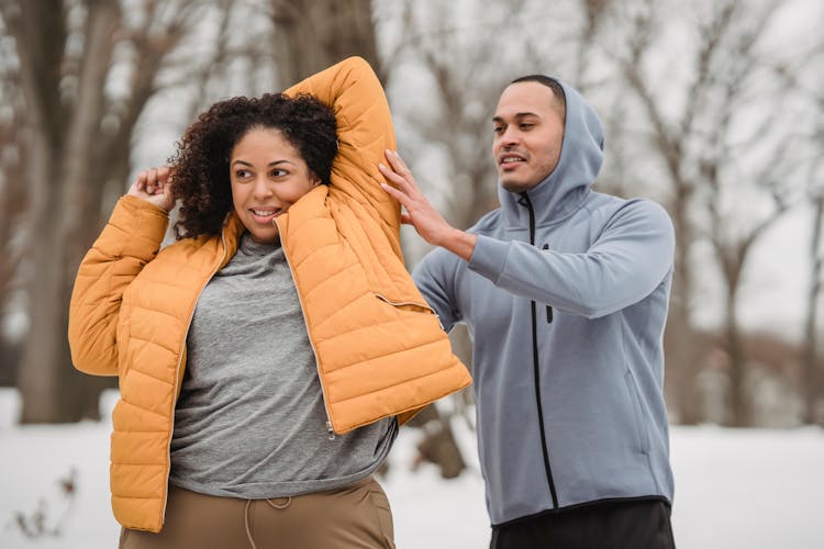 Black Woman Stretching Arm With Help Of Trainer