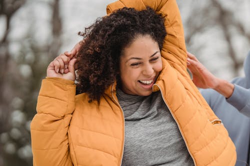 Free Cheerful African American female with curly hair smiling happily while doing warm up exercise during weight loss training with trainer Stock Photo