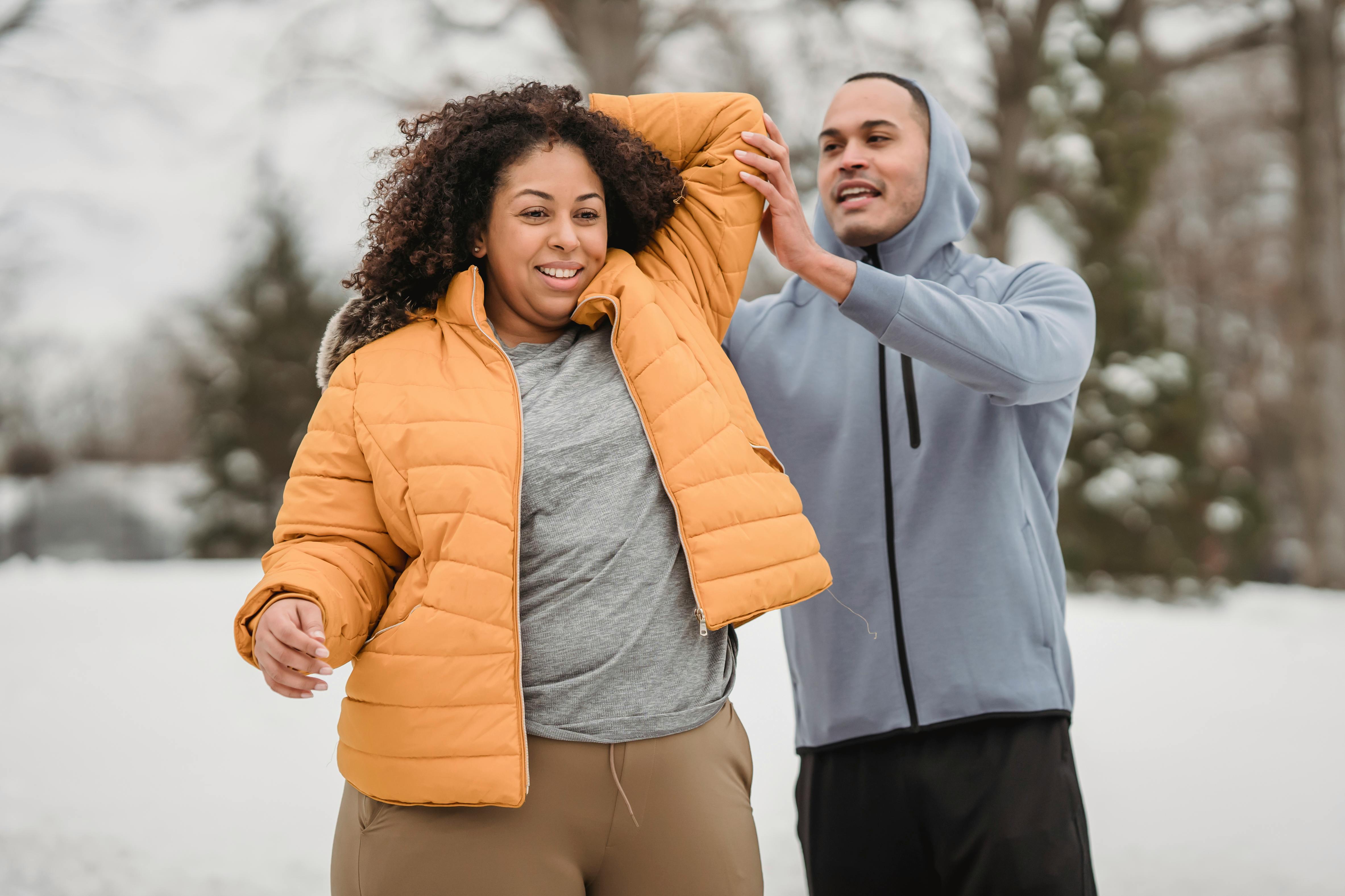 smiling black male trainer supporting woman in exercise