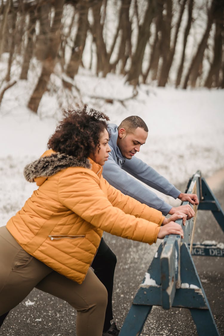 Sporty Black Couple Near Wooden Barrier In Woods