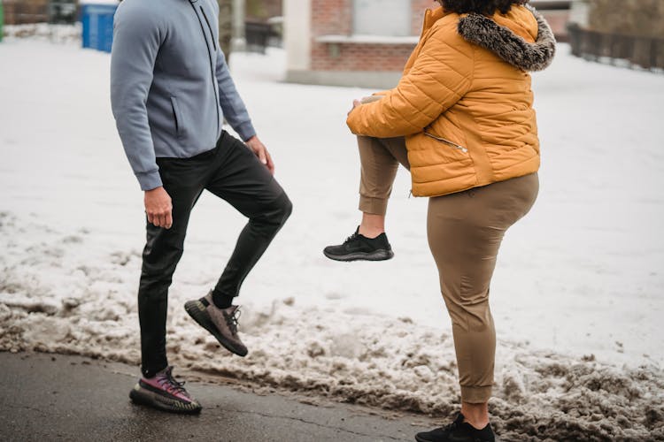 Crop Couple Stretching Legs On Snowy Street