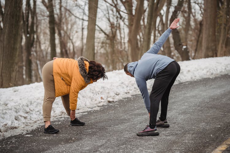 Unrecognizable Black Couple Stretching In Snowy Park