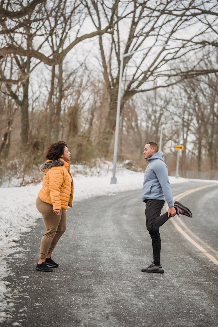 Sporty Black Couple Warming Up On Snowy Road