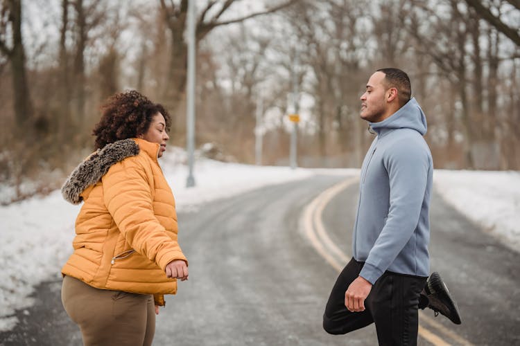 Black Couple Stretching In Snowy Park