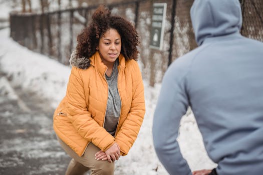 Woman exercising outdoors in winter with personal trainer for fitness and wellbeing.