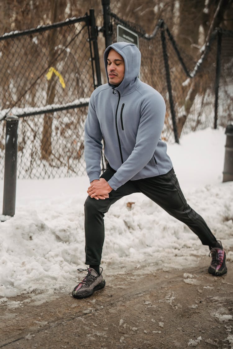 Sporty Black Man Warming Up In Winter Park