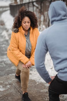 A woman and her coach engage in a winter workout outdoors, showcasing dedication and fitness.