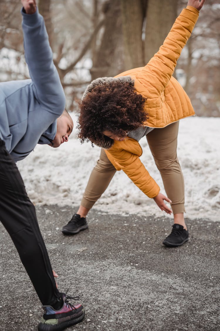 Sportive Black Couple Warming Up On Pathway In Snowy Park