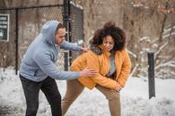 Caring black coach helping plump African American woman to do exercise
