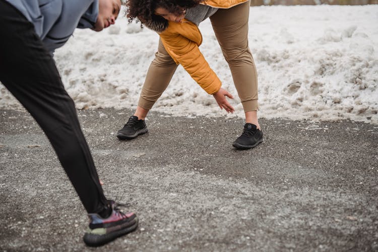 Crop Black Couple Stretching On Asphalt Path In Winter Park