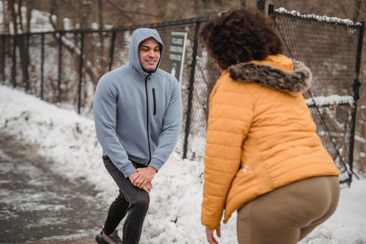 Professional trainer showing anonymous overweight woman exercises while training together in snowy park