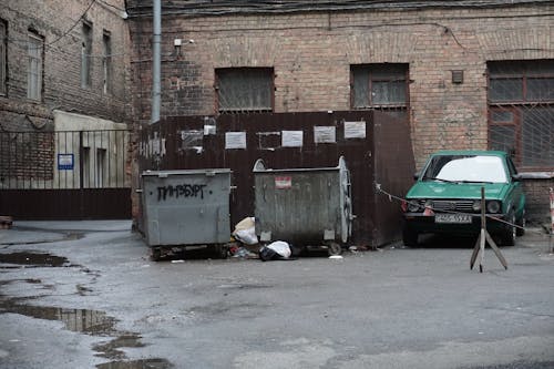 Green Car Parked Beside A Dumpsite