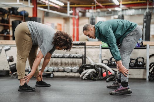 Two adults practicing stretching exercises in a modern gym setting. Enhance your fitness routine with this vibrant workspace.