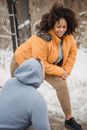 Glad overweight African American female warming up while talking with crop anonymous instructor in winter park