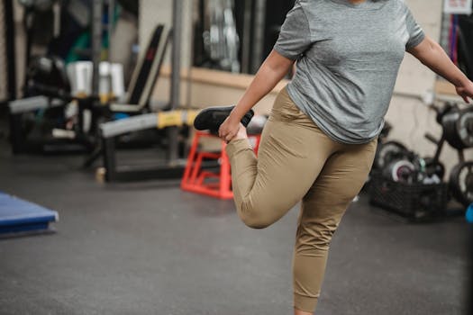A plus size woman stretches in a gym, focusing on fitness and wellbeing.