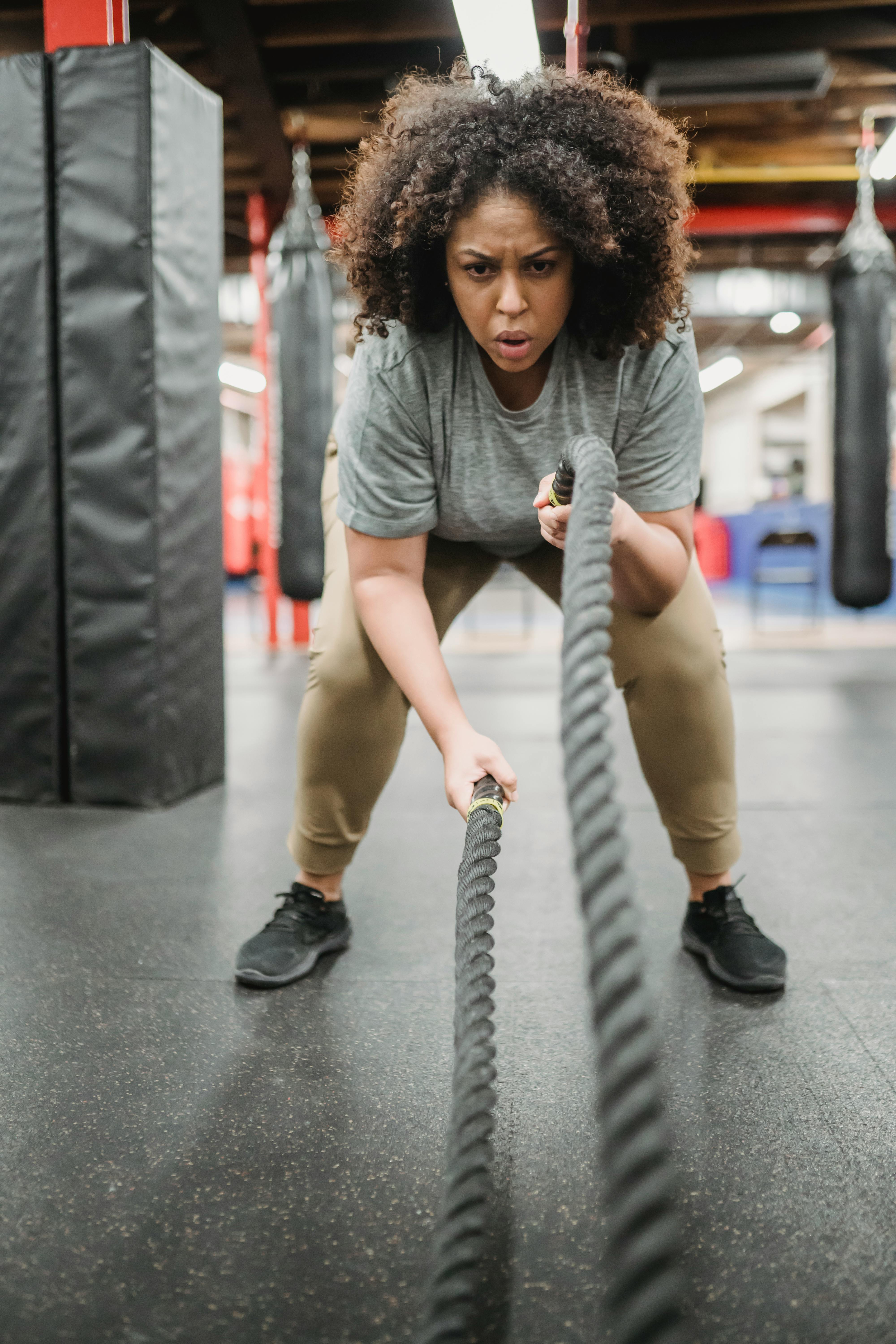 strong obese black woman exercising with heavy ropes in gym