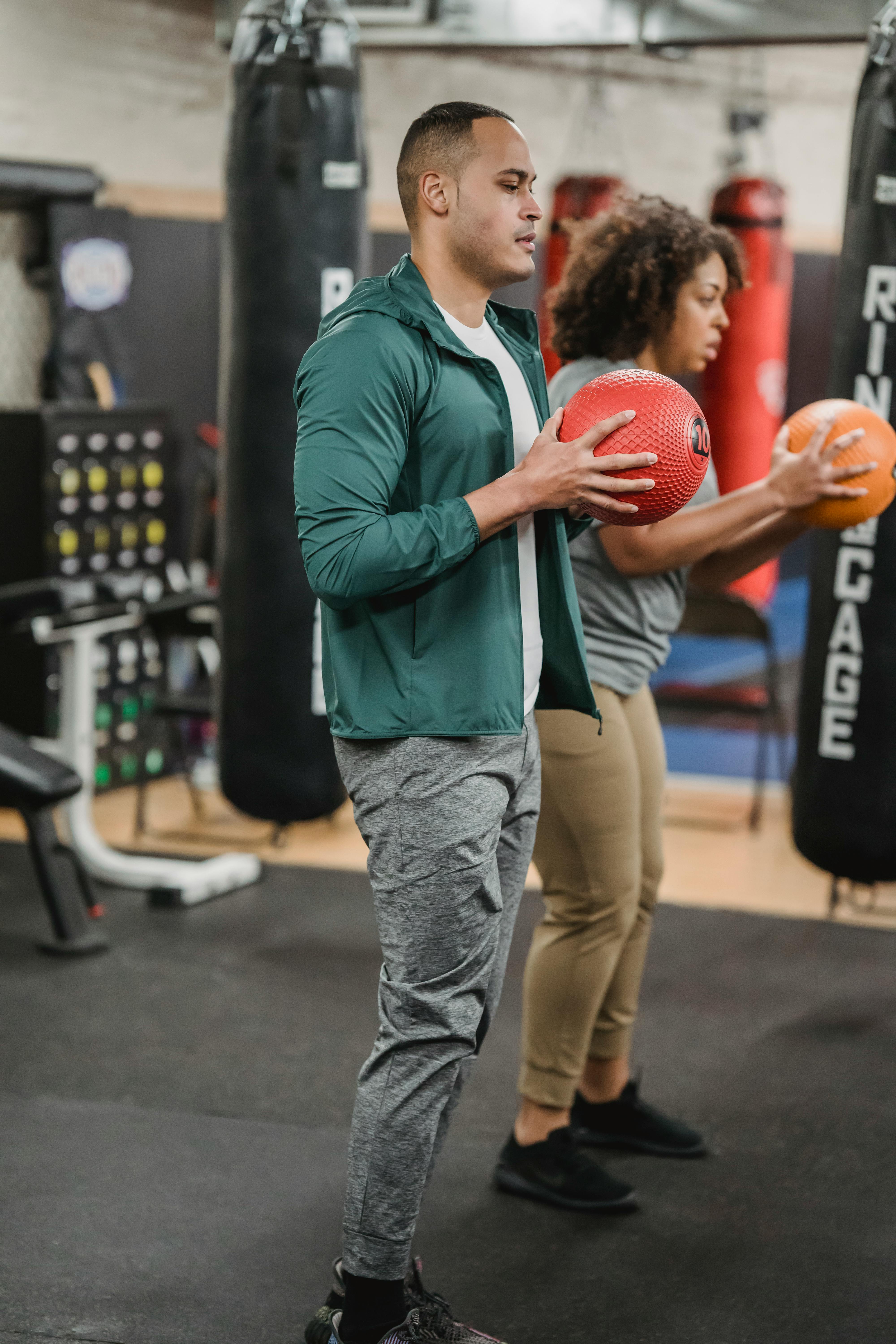 young multiethnic trainer and client doing exercise with medicine balls