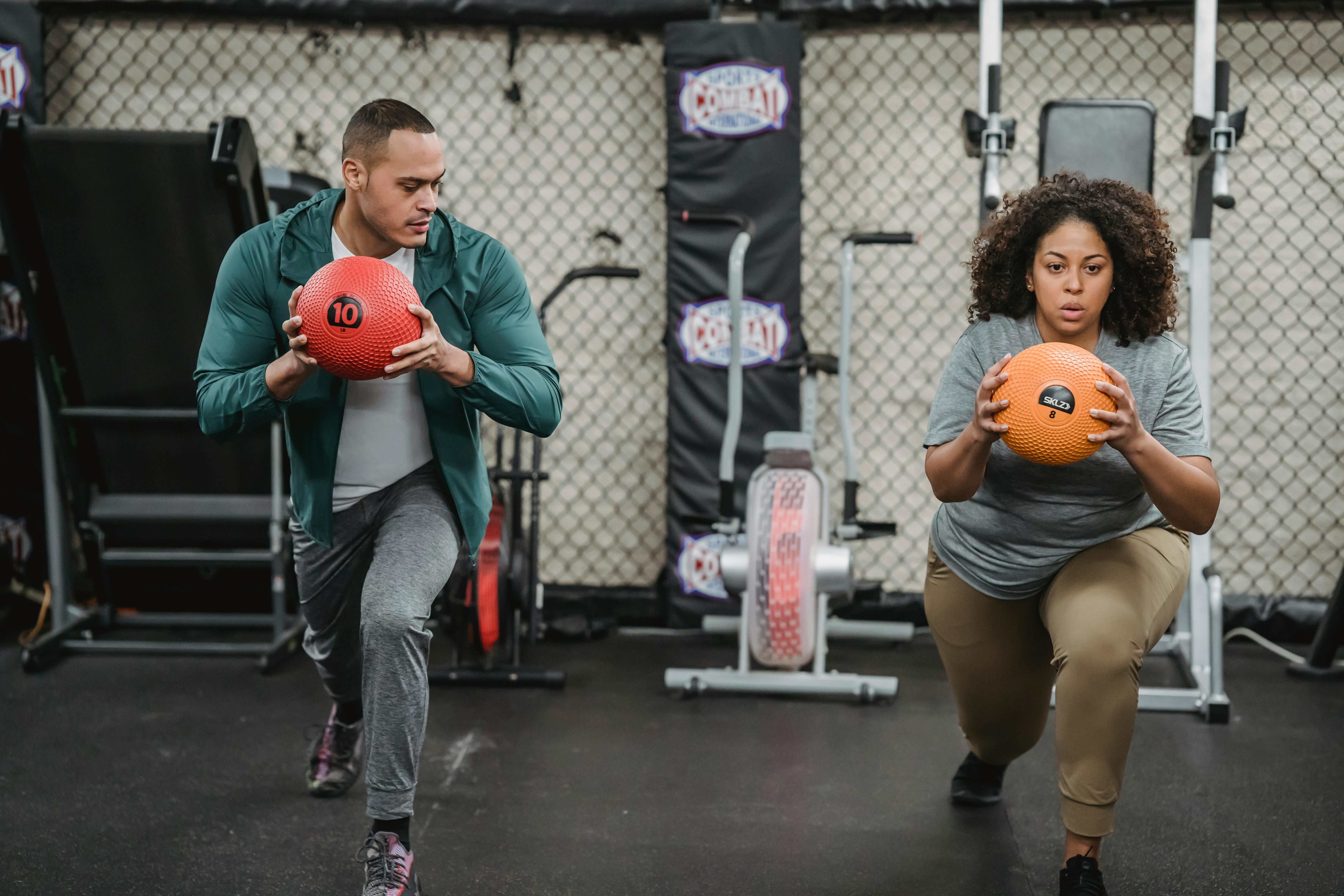 Multiethnic fit man and obese woman with medicine ball doing lunges in sports club