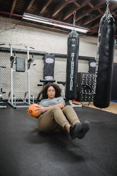 Plus-size woman performing core exercises with a medicine ball in a modern gym setting.
