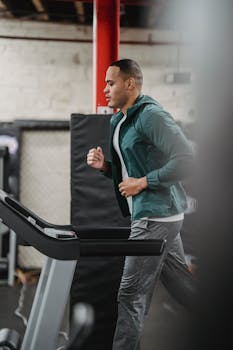 Side view of focused male in activewear jogging on treadmill in modern sport club