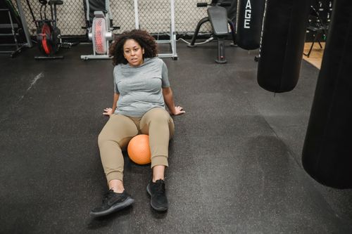 Free From above of plump African American overweight female exercising with ball on floor in sport club Stock Photo