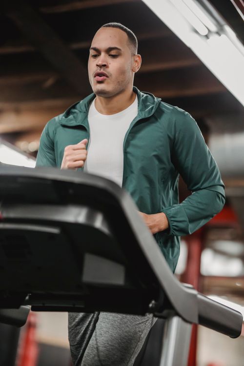 Free From below of concentrated male in activewear running while watching on screen of treadmill Stock Photo