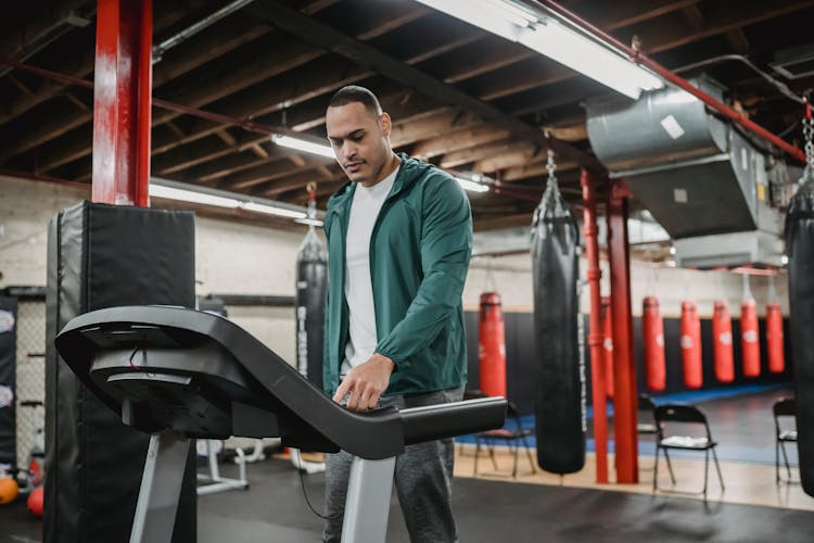 Man Regulating Speed On Modern Treadmill