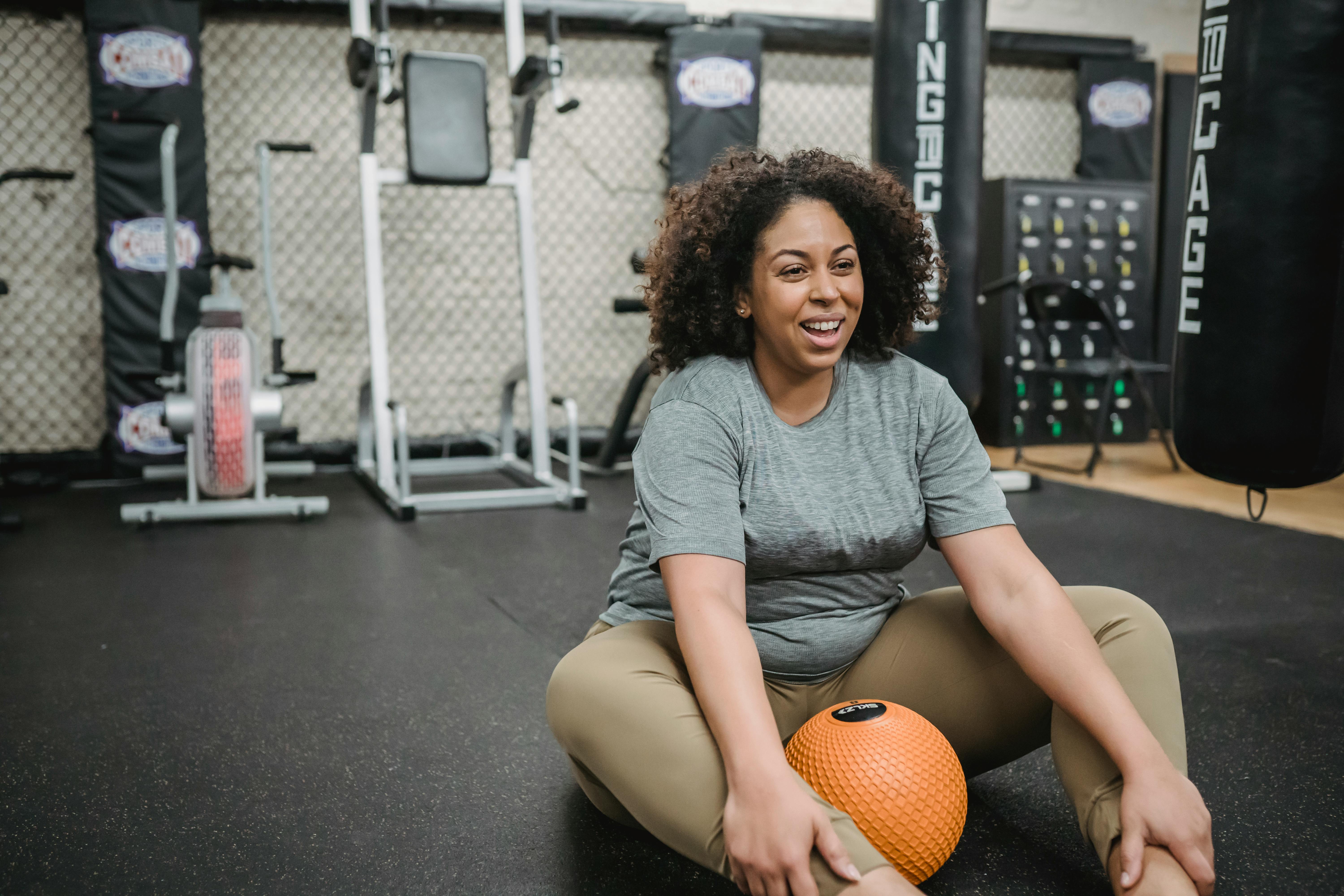 cheerful overweight black woman smiling and training in gym