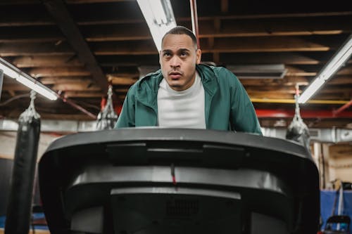 Free Concentrated male in sportswear training on treadmill and losing weight in contemporary sport club Stock Photo