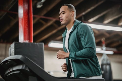 Free Serious man running on treadmill and watching on display Stock Photo