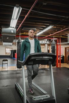Full body of fit male in sportswear exercising on treadmill in modern sport club
