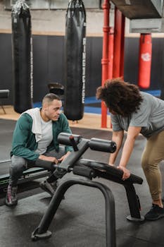 Personal trainer guiding a client during an exercise session in a modern gym setting.