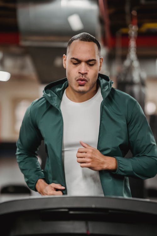 Free Serious man watching at display of treadmill and running Stock Photo