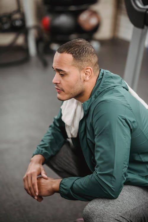 Free Side view of professional thoughtful coach in sportswear resting after working out on blurred background of gym Stock Photo