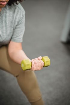 Close-up of woman exercising with a dumbbell in a modern gym setting.