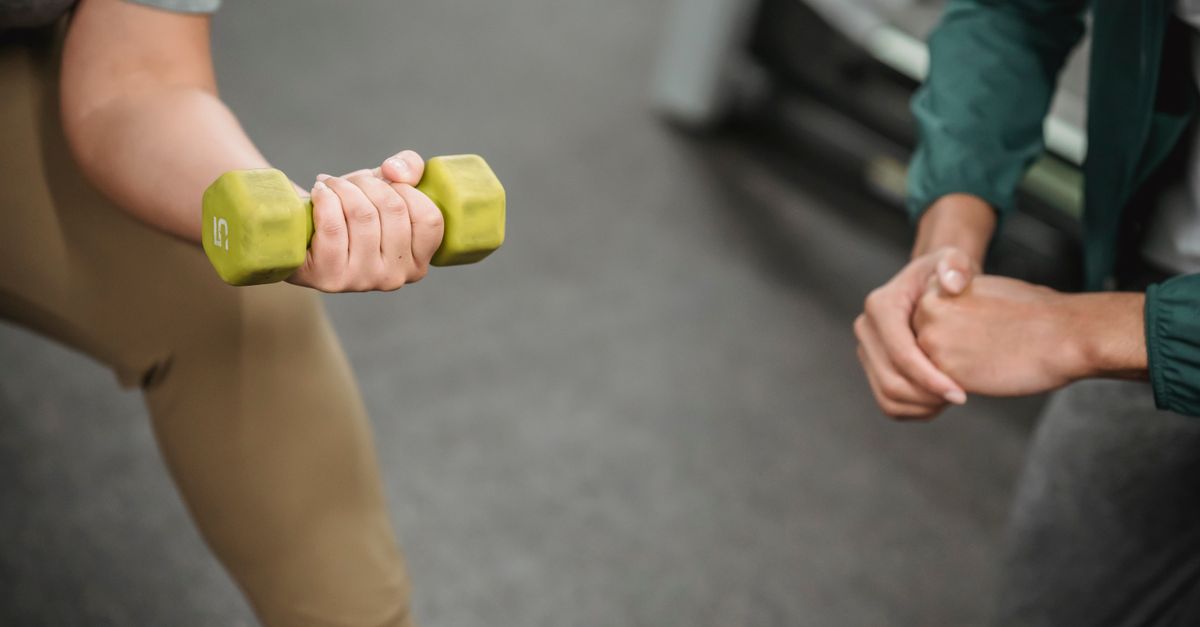 Strong woman lifting dumbbell while trainer watches