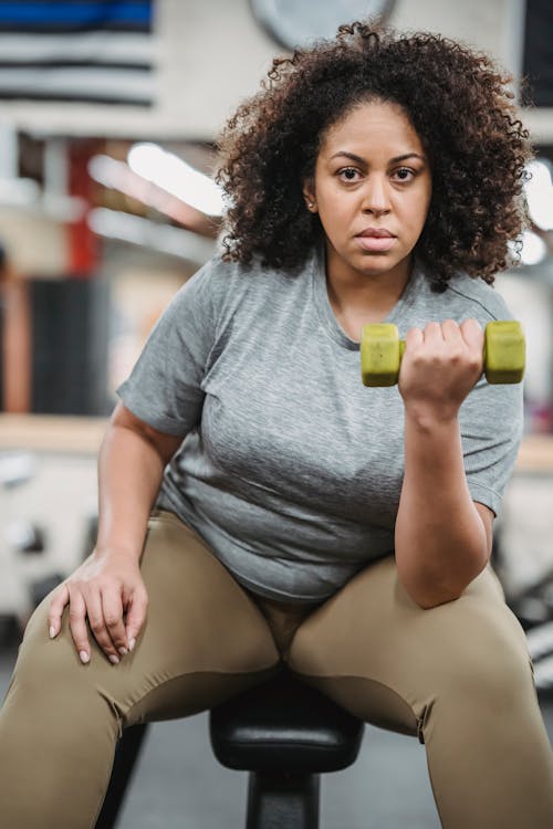 Overweight black woman lifting dumbbell in gym