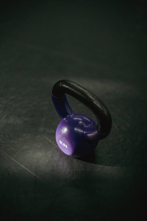 Free From above of single violet kettlebell with handle for weight training on black background Stock Photo