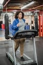 Full body of curvy black female running on treadmill during fitness workout in gym