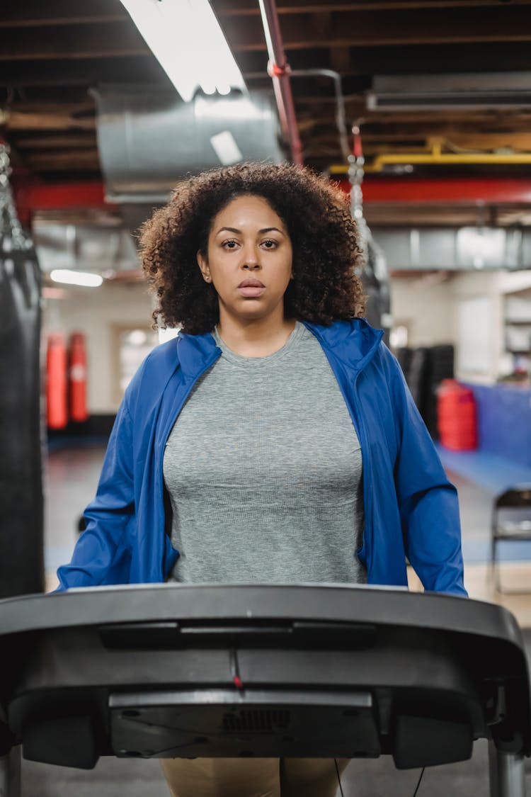 Serious Woman Walking On Treadmill During Workout