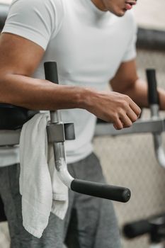 Side view of crop unrecognizable male athlete in sportswear using exercise machine during workout in gym