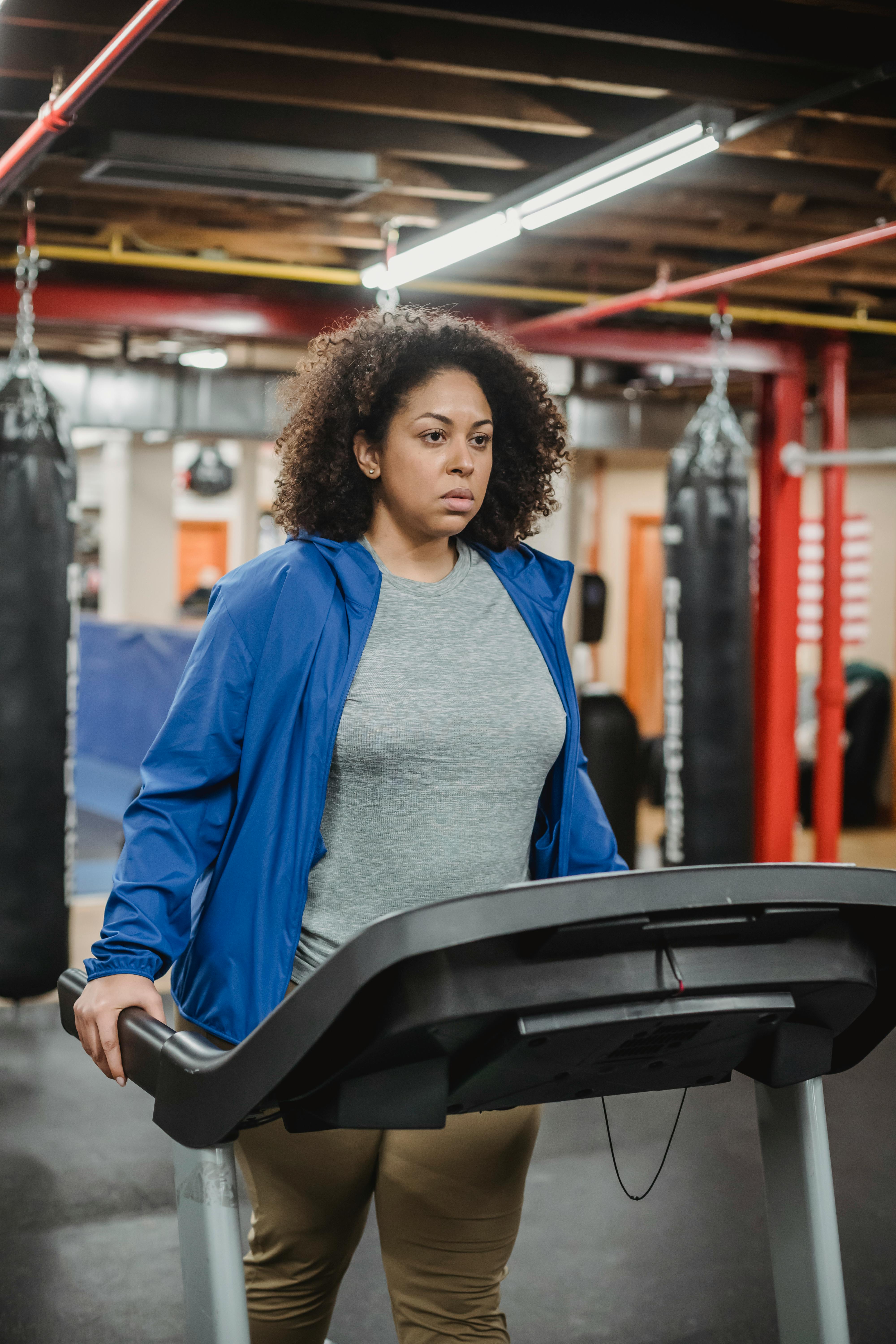 weary thoughtful woman walking on treadmill in gym