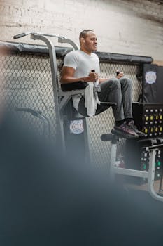 Full body of male athlete in sportswear doing knee to chest exercise on sport equipment during intense workout