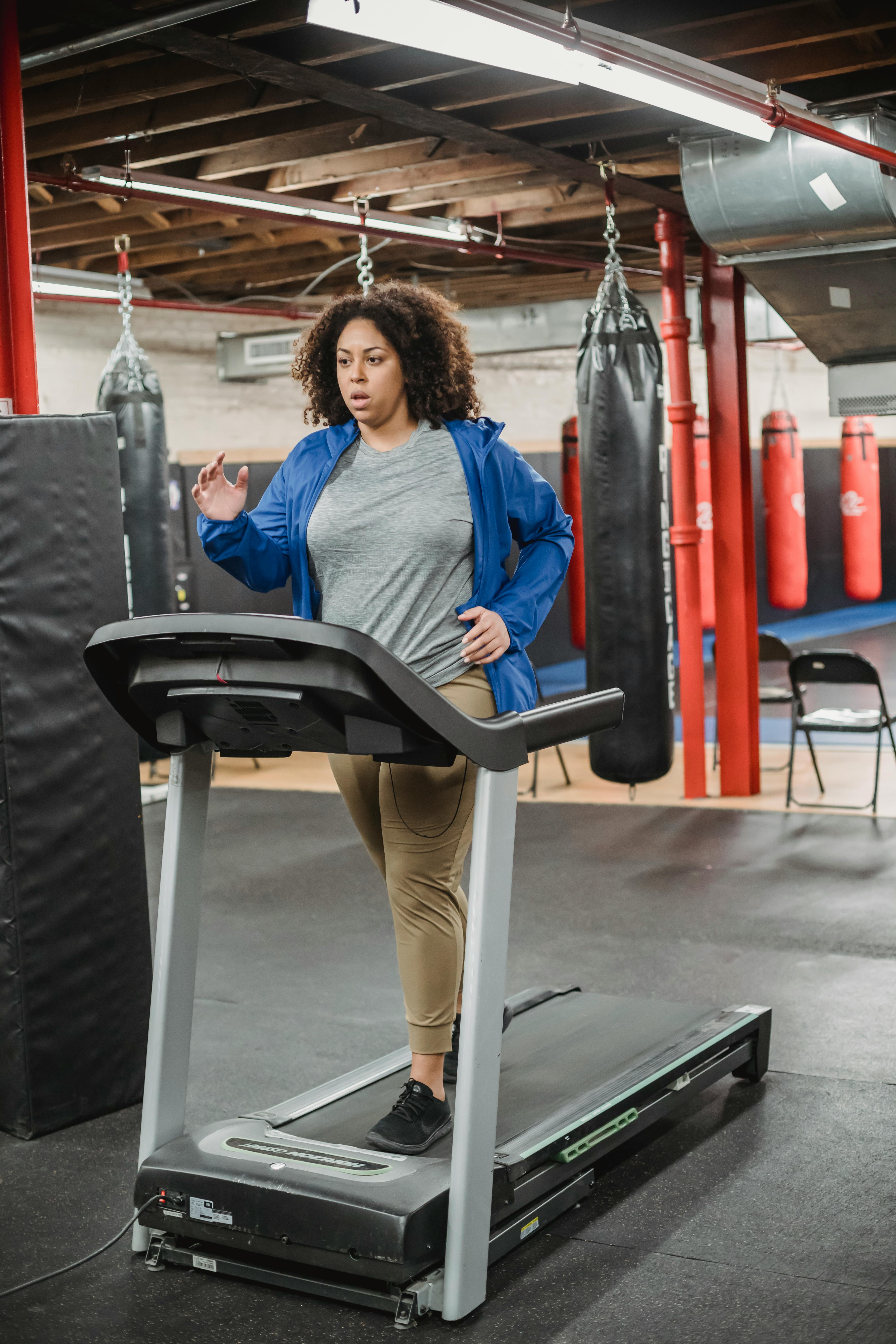 Tired woman running on treadmill in contemporary gym