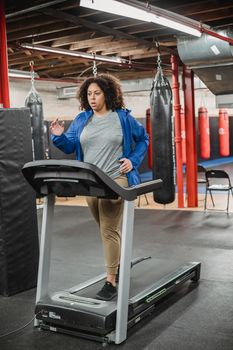 Focused plus size woman exercising on treadmill in gym, promoting fitness and healthy lifestyle.