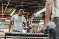 Crop black man doing exercise with dumbbells